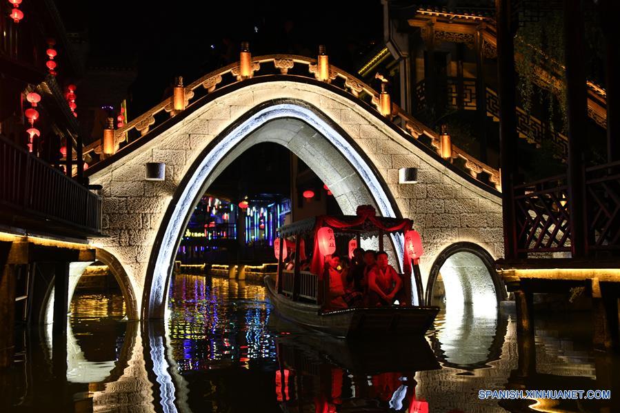 Turistas toman botes turísticos de noche en la zona escénica del antiguo pueblo de Taierzhuang