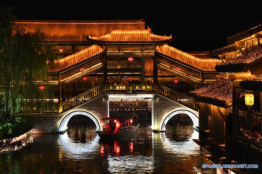 Turistas toman botes turísticos de noche en la zona escénica del antiguo pueblo de Taierzhuang