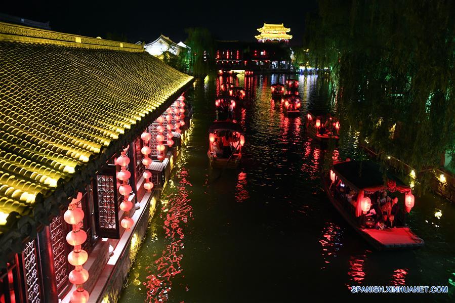 Turistas toman botes turísticos de noche en la zona escénica del antiguo pueblo de Taierzhuang